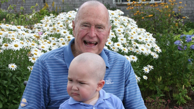 President George H. W. Bush shaves his head in solidarity for a young cancer patient.
