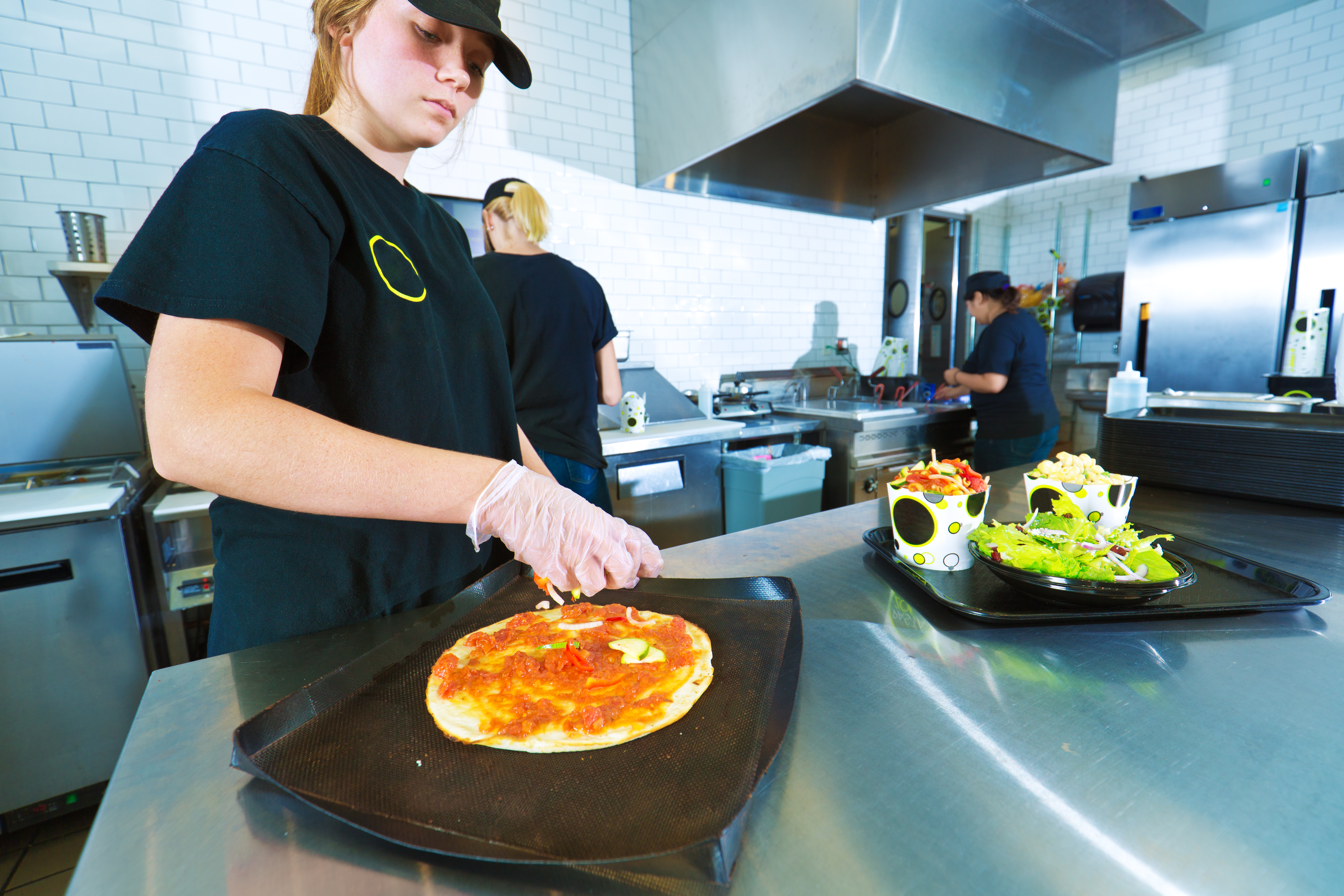 Picture of woman dressing pizza