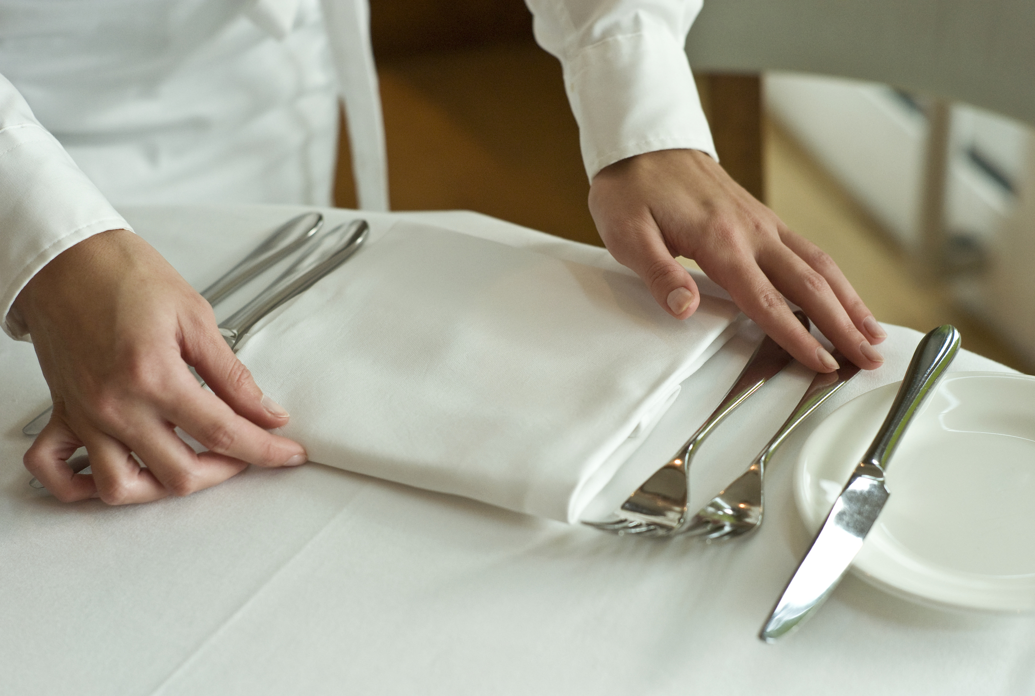 Picture of Waitress adjusting table settings in restaurant, mid section